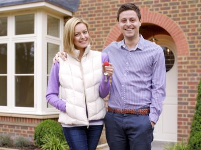 Couple holding keys to their house in front of their house