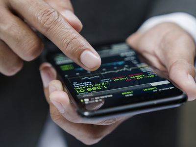 A man uses a phone to look at trading data