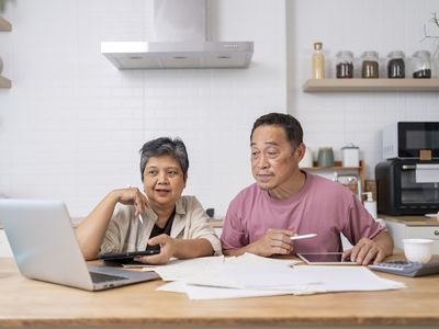 Happy Asian senior couple looking at their insurance options on laptop