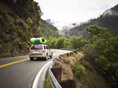 Car with Kayaks Driving Windy Road in Mountains