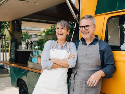 Happy mature couple looking away while standing against food truck