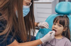 A female dentist examines a little girl's teeth