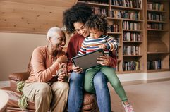 Grandmother, mother, and child looking at a tablet.