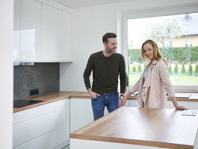 A man and a woman stand in a kitchen of a new house