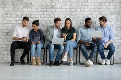 Three couples sitting in a row holding tablets and talking to each other