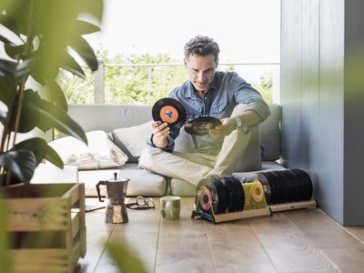 A mature man sitting at home, looking at vintage sigle recors.