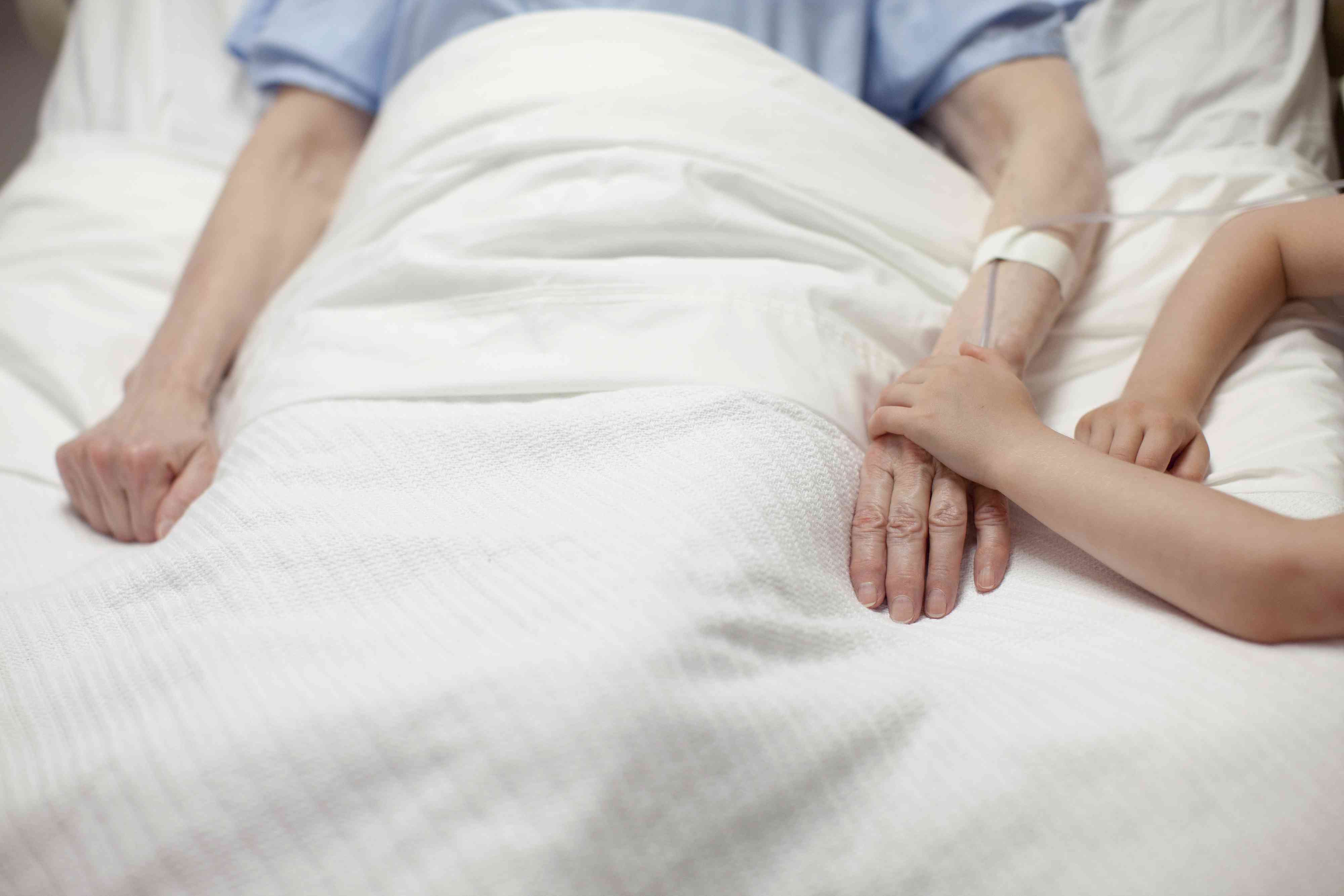 Young girl holding grandma's hand in hospital short term disability