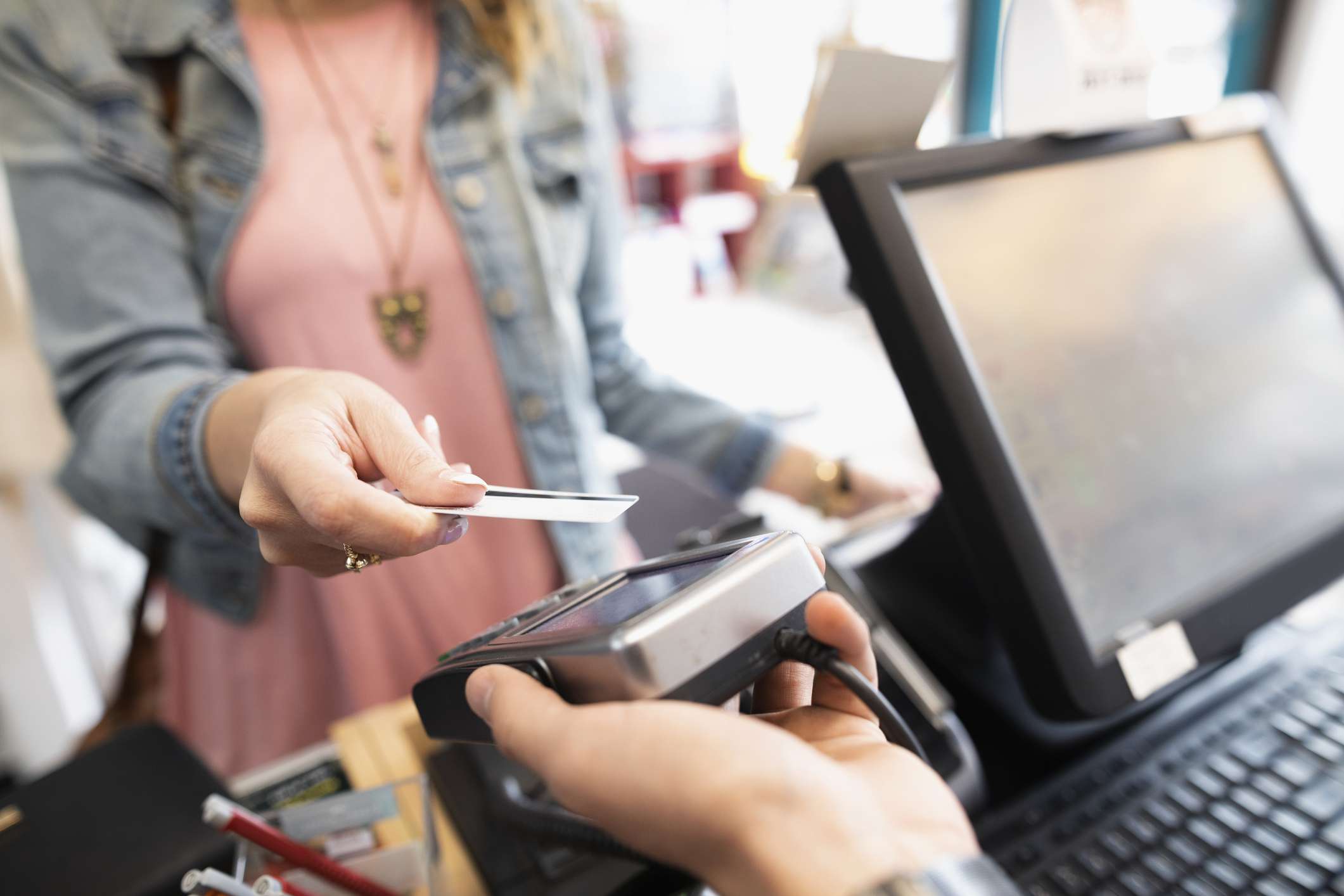 Female shopper paying with contactless credit card in shop