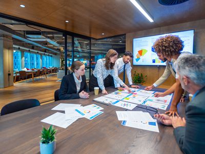 Paperwork and group of peoples hands on a board room table at a business presentation or seminar