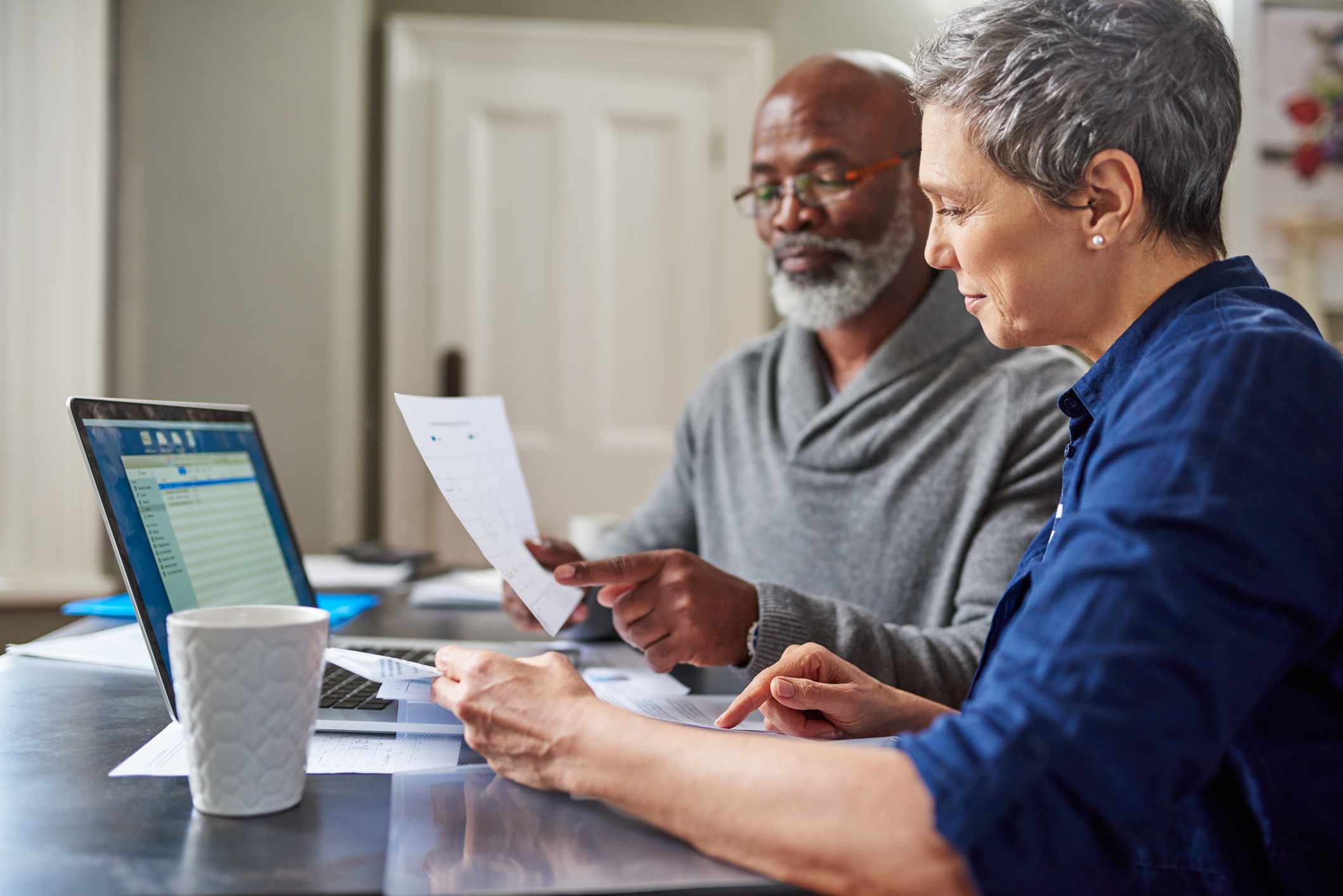 Senior couple at computer looking over retirement paperwork