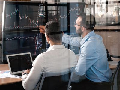 Two traders compare indexes on shown on computer screens in an attempt to predict market trends.