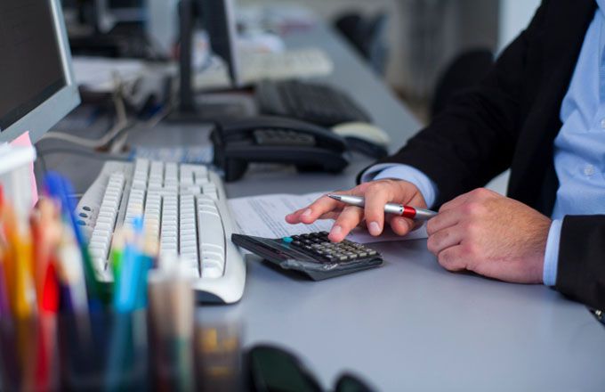 man at desk with calculator