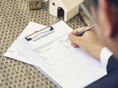 Loan officer signing as Lender with a pen on the loan agreement for a mortgage. 