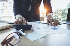 Close up Businessman using calculator for do math finance on wooden desk in office, tax, accounting, statistics and analytic research concept