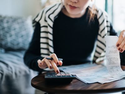 Young person managing personal banking and finance at home with a calculator