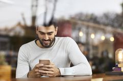 A man uses a cell phone in a cafe.