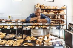 Bakery owner standing in their bakery looking out for customers in an empty store during a sluggest market.