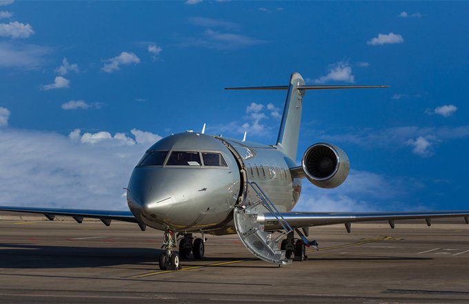 A sleek private jet waiting on the runway with the boarding ladder down.