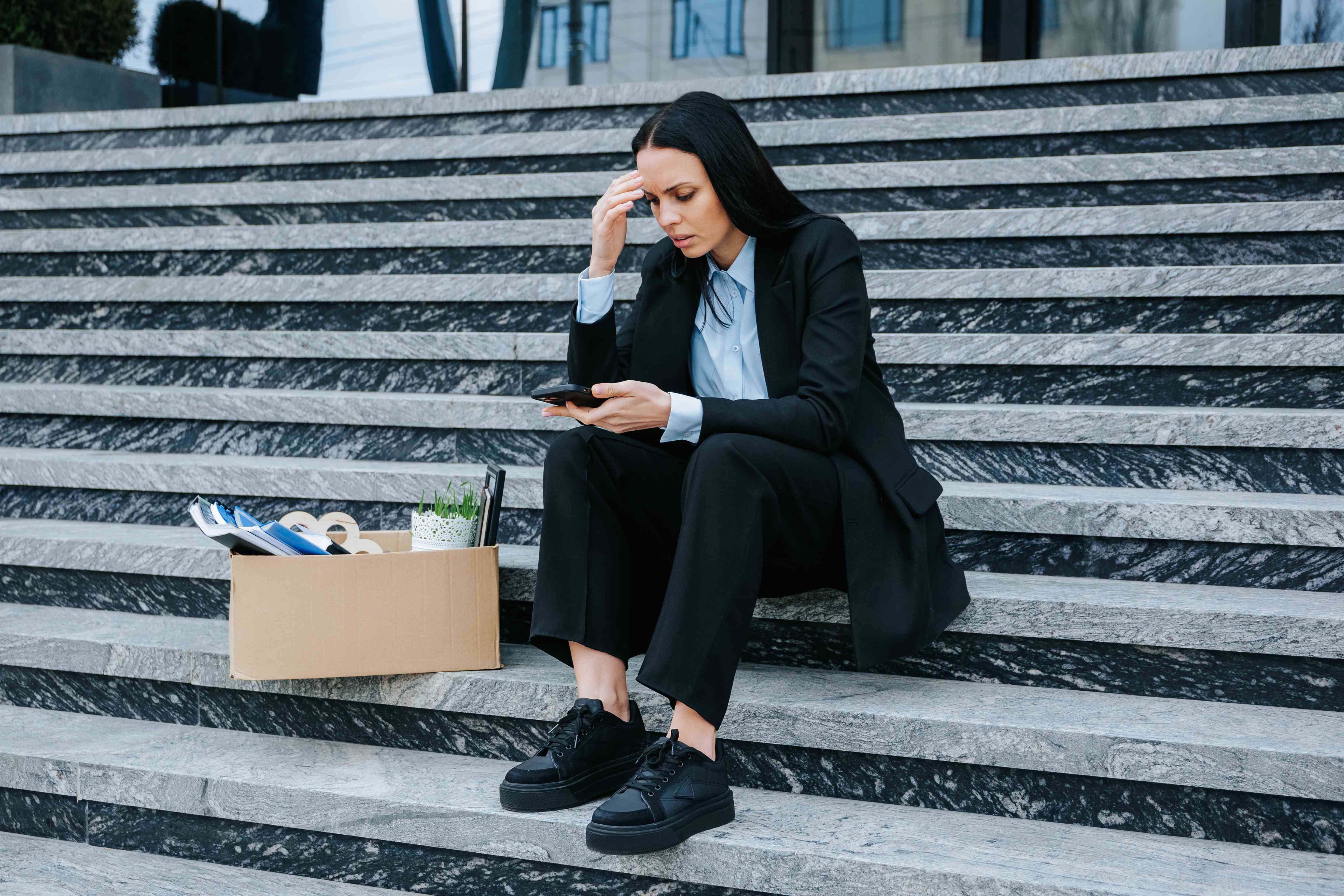 Woman looking at her phone to prepare filing a claim for wrongful termination