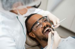 A dentist examines a young man's teeth in her office