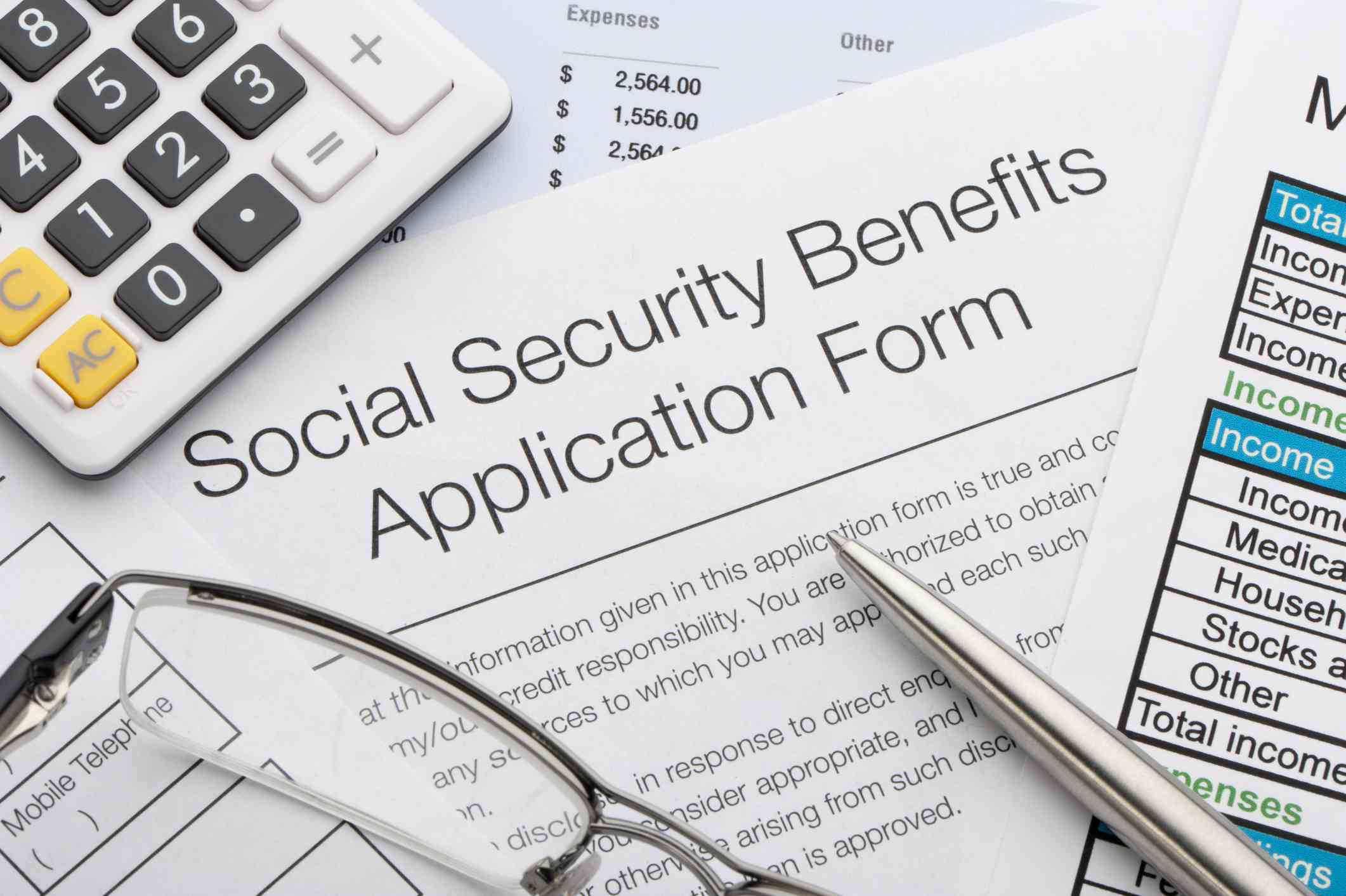 A Social Security application with calculator, eyeglasses, and pen.