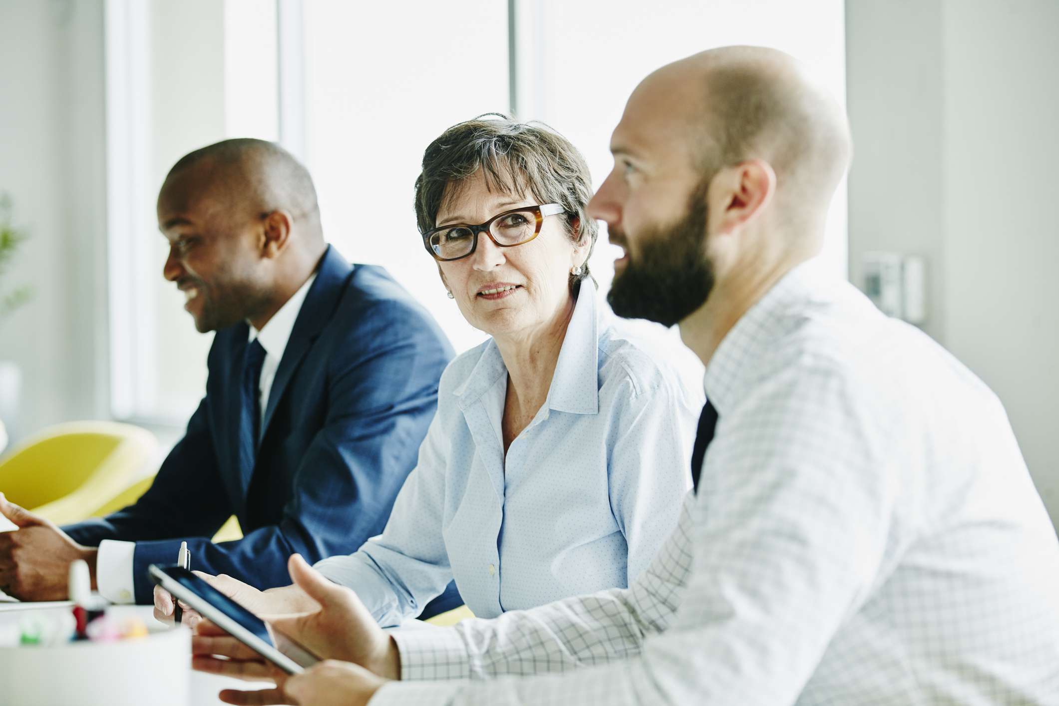 Three executives have a discussion in a boardroom.