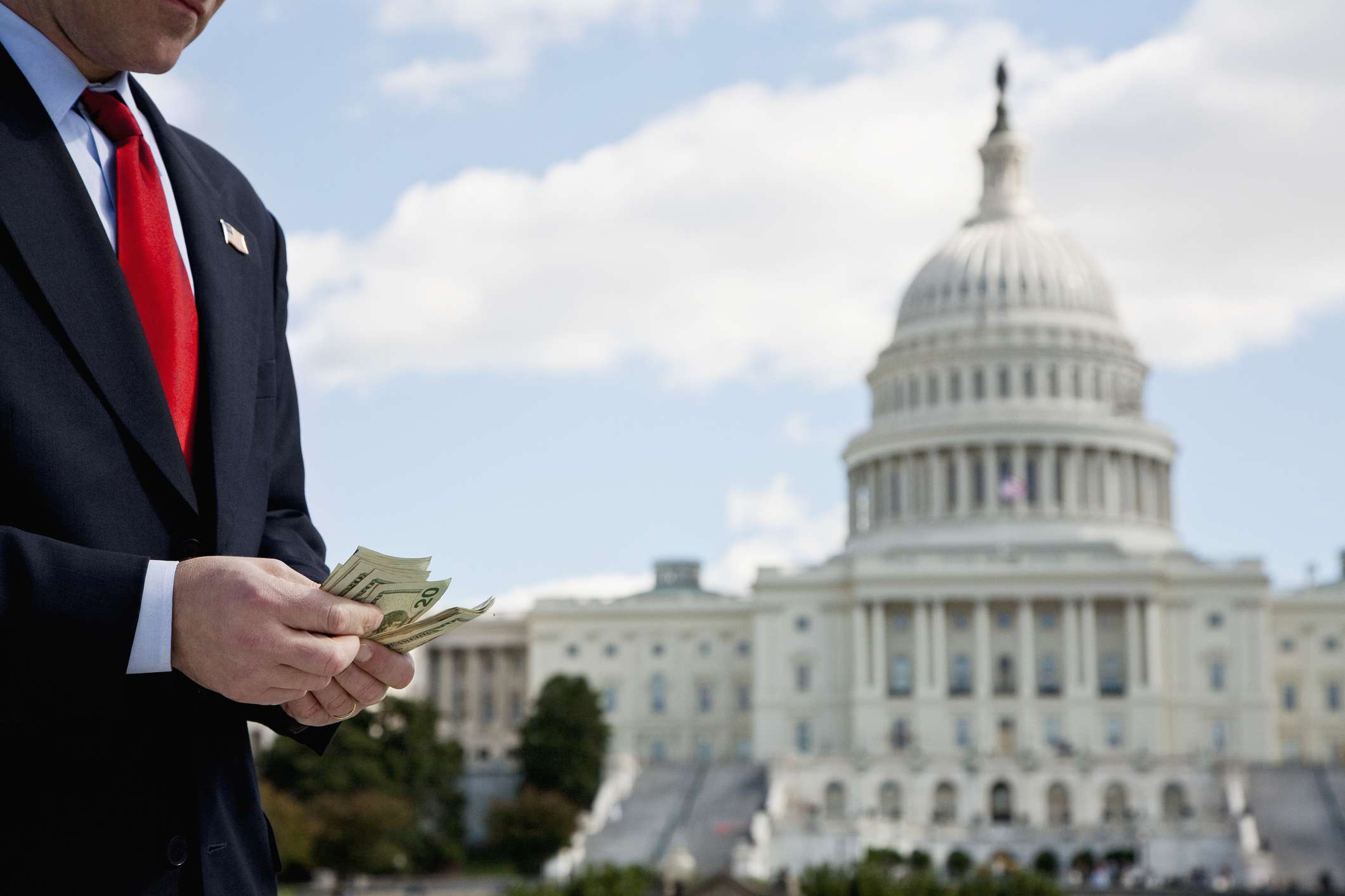 A politician counting money in front of the US Capitol Building.