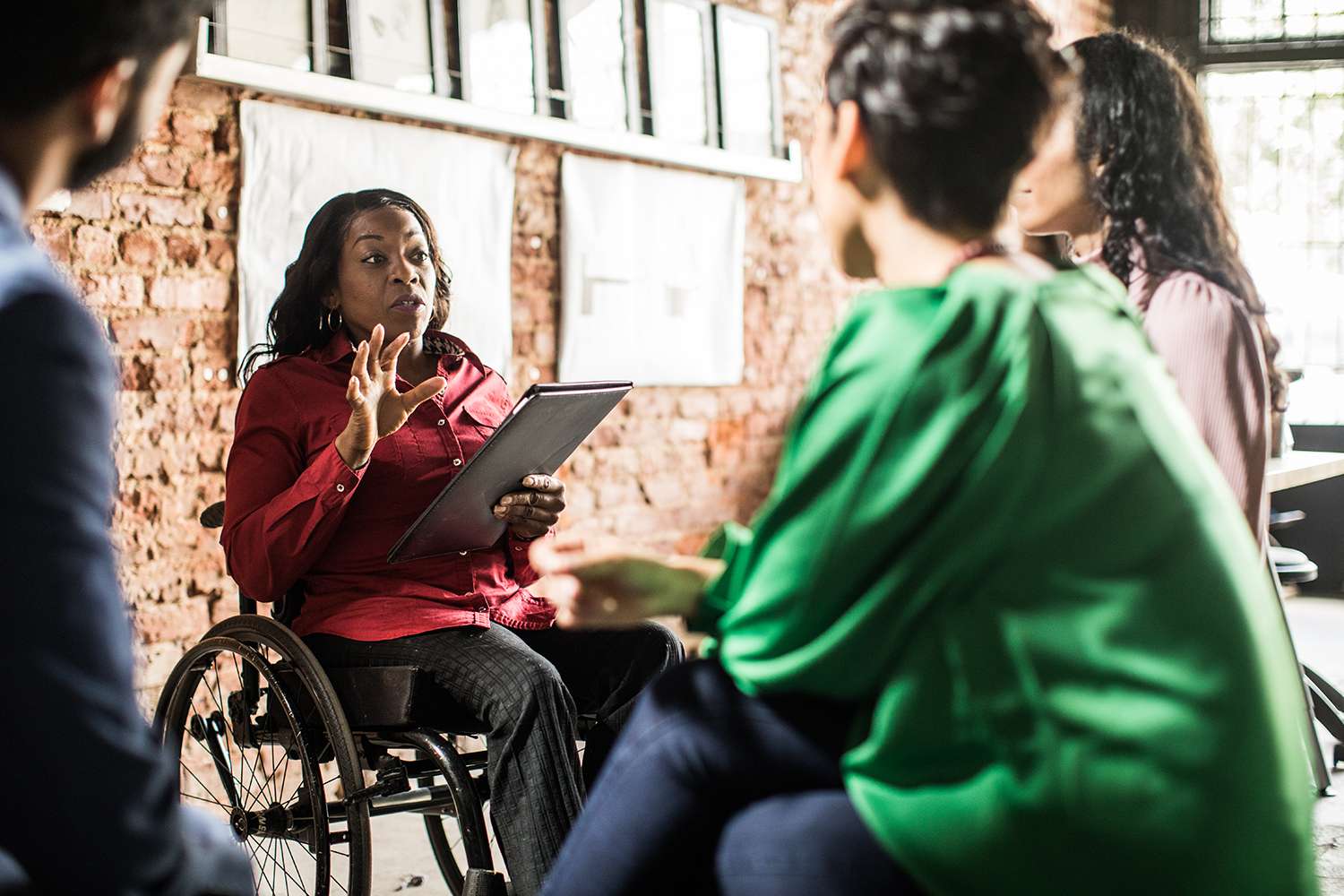 Businesswoman in wheelchair leading group discussion about disability insurance for the self-employed