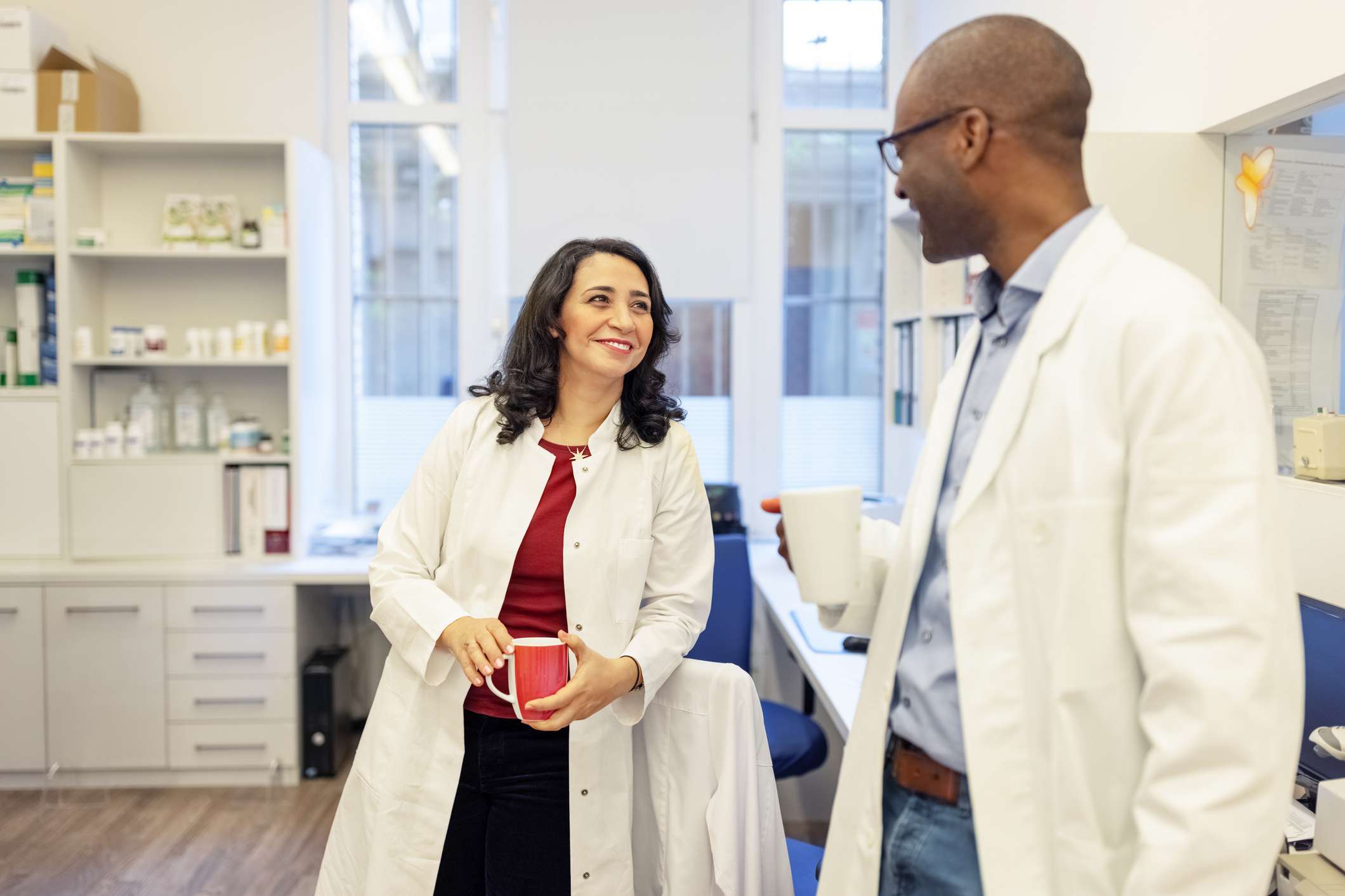 Pharmacist chatting with colleague during coffee break while in pharmacy