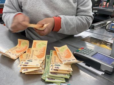 A cashier counts Argentine pesos bills at a supermarket in Buenos Aires while the Argentine peso suffers constant depreciation against the US dollar