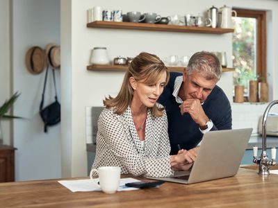 A senior couple planning their finance and paying bills while using a laptop at home