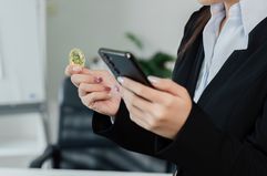 Person holding a coin and looking at phone