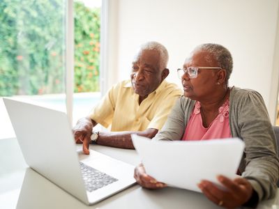 Older couple working together on laptop at home