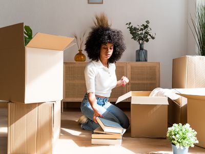 A woman unpacks boxes of books.