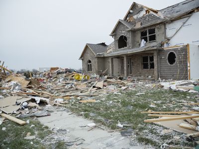 House destroyed by tornado, surrounded by pieces of furniture and and trash.