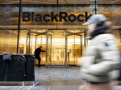 The BlackRock name appears above two revolving doors at the company's headquarters, as people walk by on the sidewalk out front.