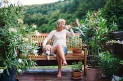 Elderly woman sipping coffee outdoors with her dog