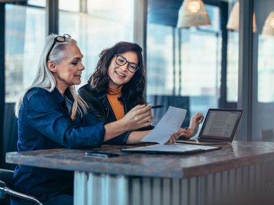 Two women analyzing documents at office