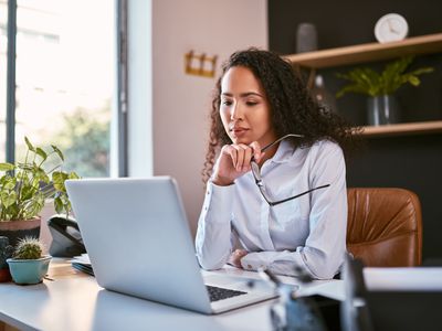 A young woman sitting at a desk and looking at a laptop