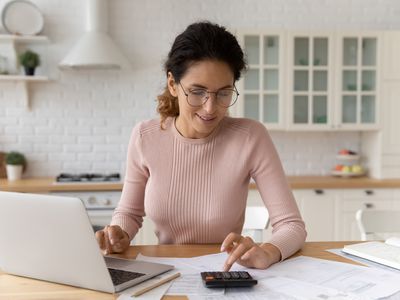 Woman using a calculator and computer while doing paperwork