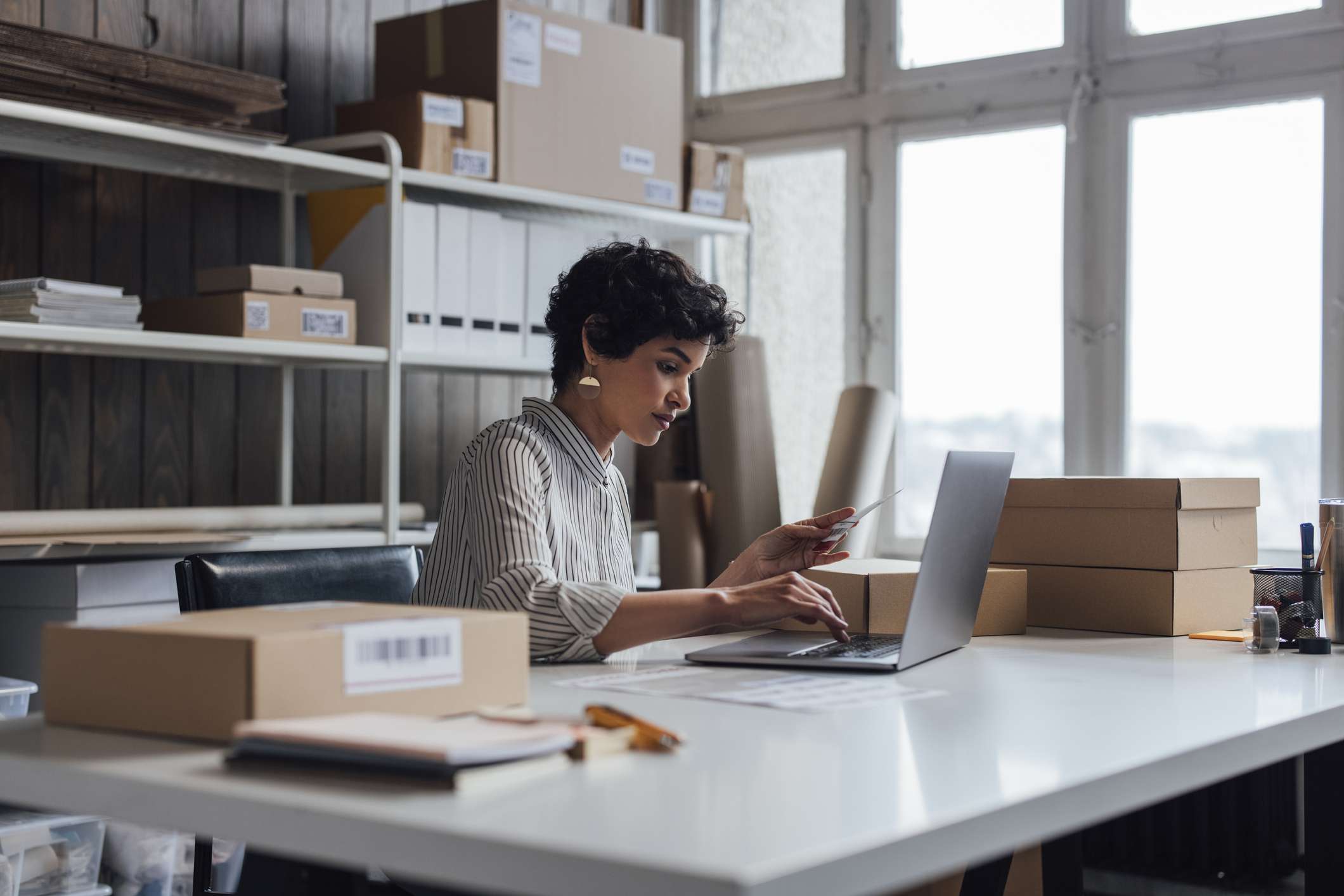 A young small business owner using her laptop computer to check a customer’s order details on her website