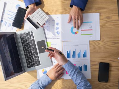 Two business accountants review printouts of quarterly company performance and discuss changing the amount of profits paid out to shareholders based on a target payout ratio.