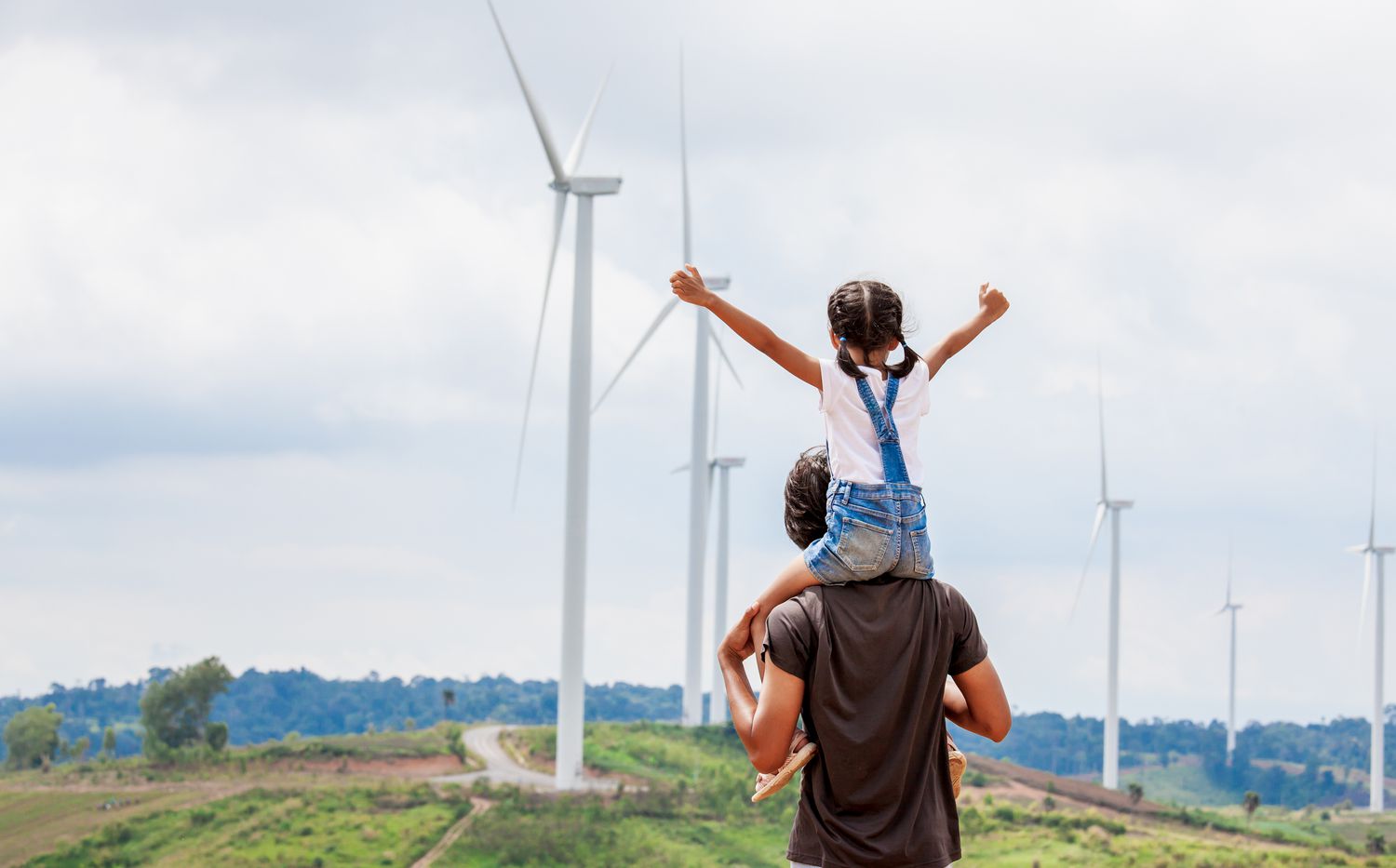 Father and daughter at a wind turbine field that provide sustainable energy.