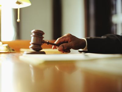 Cropped hand of a judge striking a block with a gavel