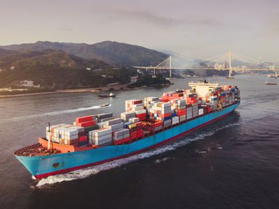 Container ship loaded with goods sailing away from a port