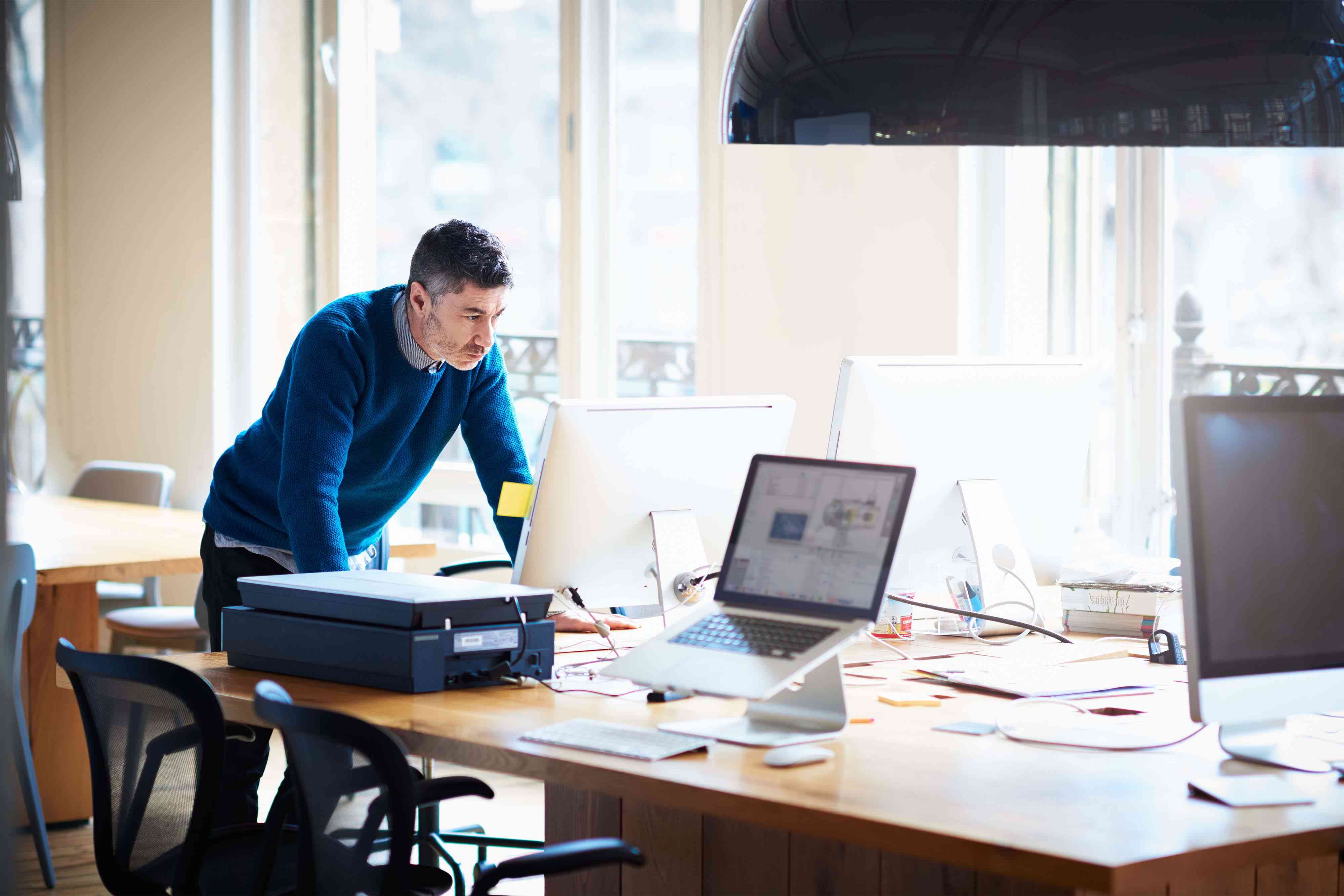 Small business startup owner standing by desk, working on a computer for a grant