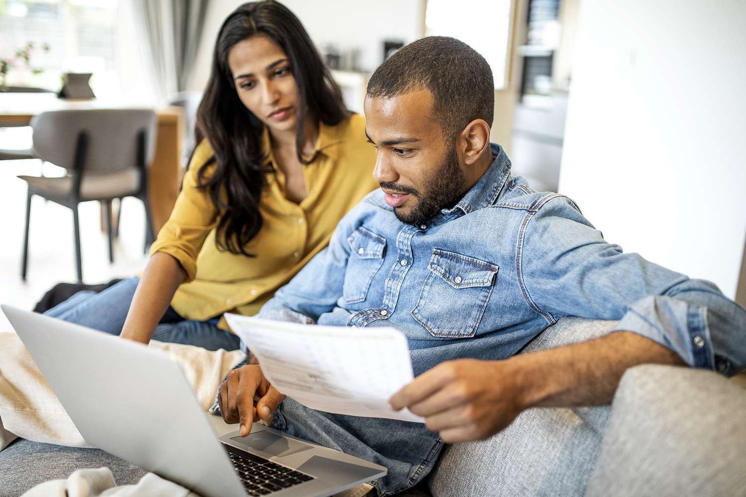 Two people look at a laptop.