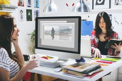 Two Female Fashion Bloggers Sitting at Desk in the Office