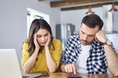 Couple sitting at a desk with a laptop and a calculator