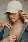 Front view of model wearing the six-panel sahara Official Cap with a curved brim and an embroidered upside down Joah Brown logo on the front